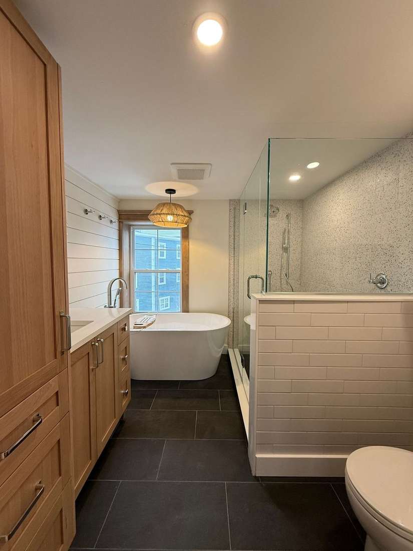 The Bond bathroom after renovation — a bright bathroom with oak cabinetry, freestanding tub, and terrazzo glass shower.