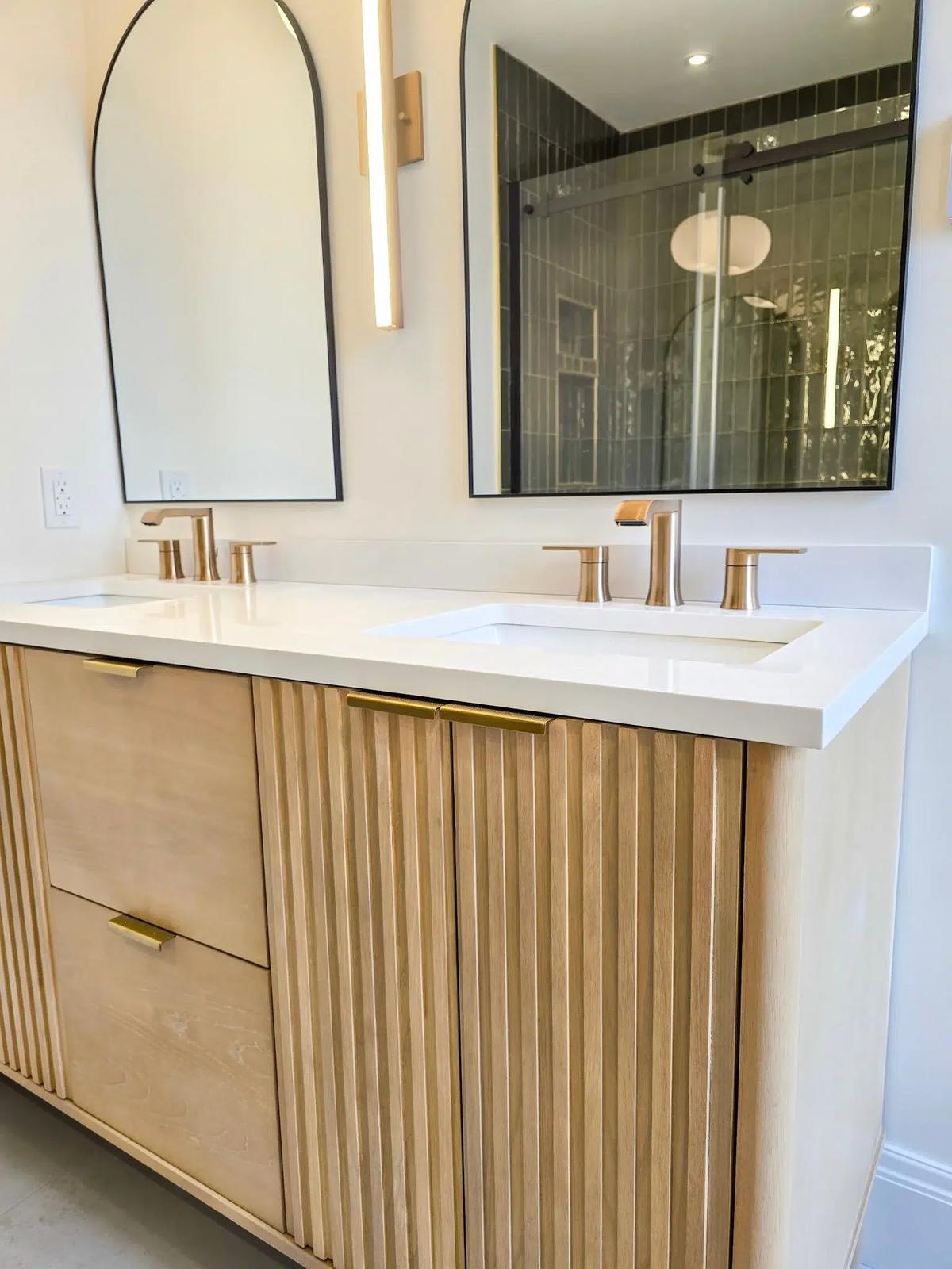 Finished bathroom from the Newtown Road renovation — double vanity with arched mirrors and fluted oak cabinetry.