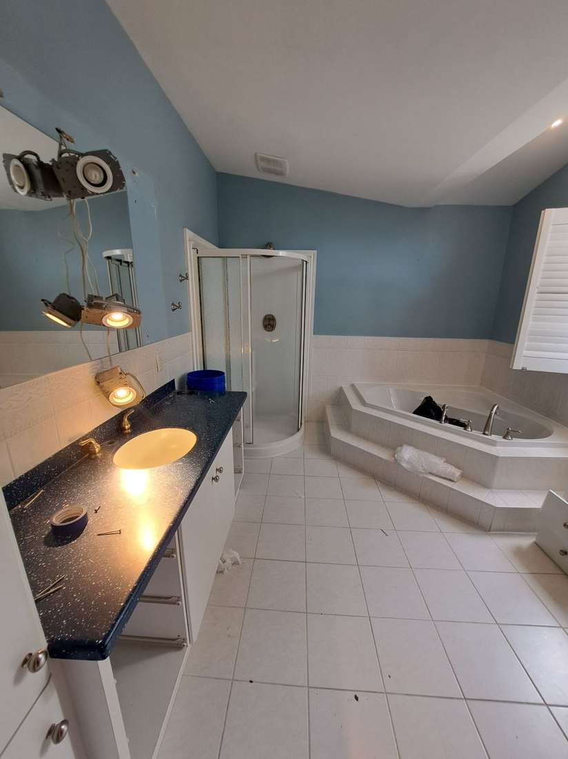 The Kensington bathroom before renovation — dated vanity, corner shower and a tiled step-up tub.