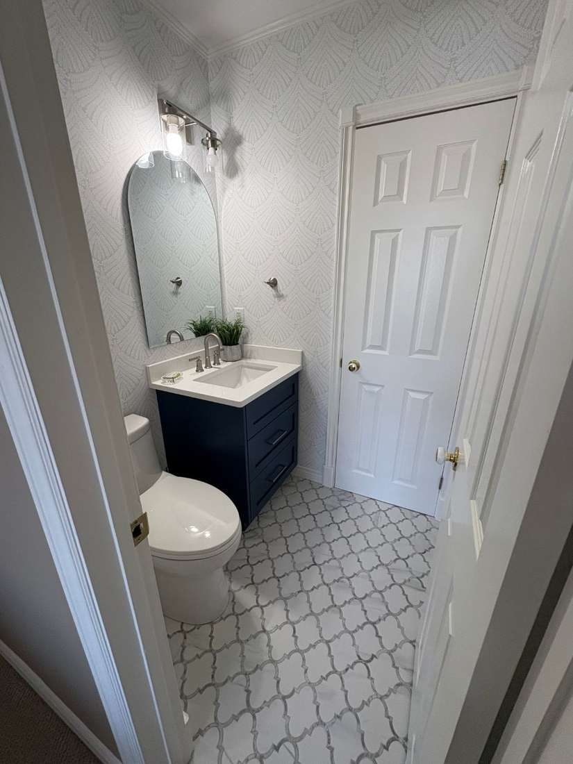 Kensington powder room — navy vanity, arabesque marble floor tile.