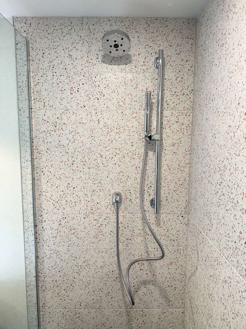 Polished chrome shower fittings against soft terrazzo tile — detail from the Bond Project.