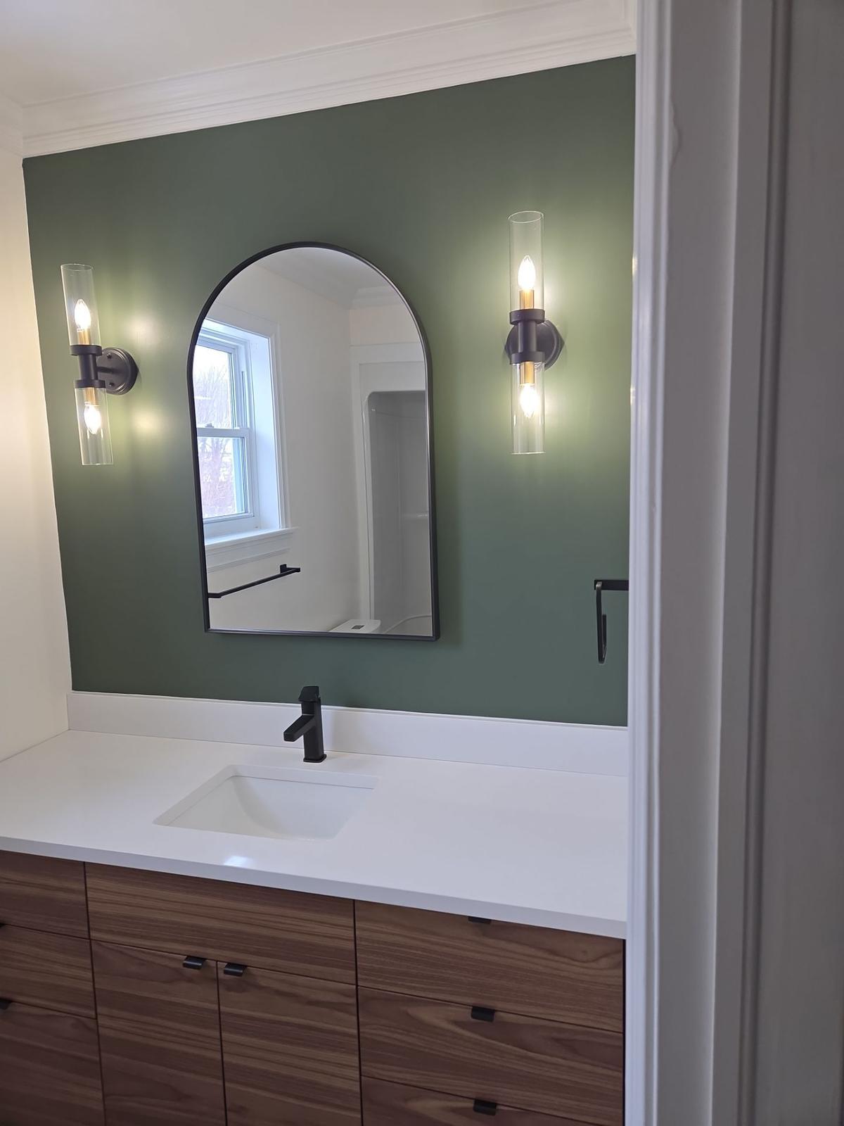 The finished Motion Lane ensuite — green accent wall and arched mirror.
