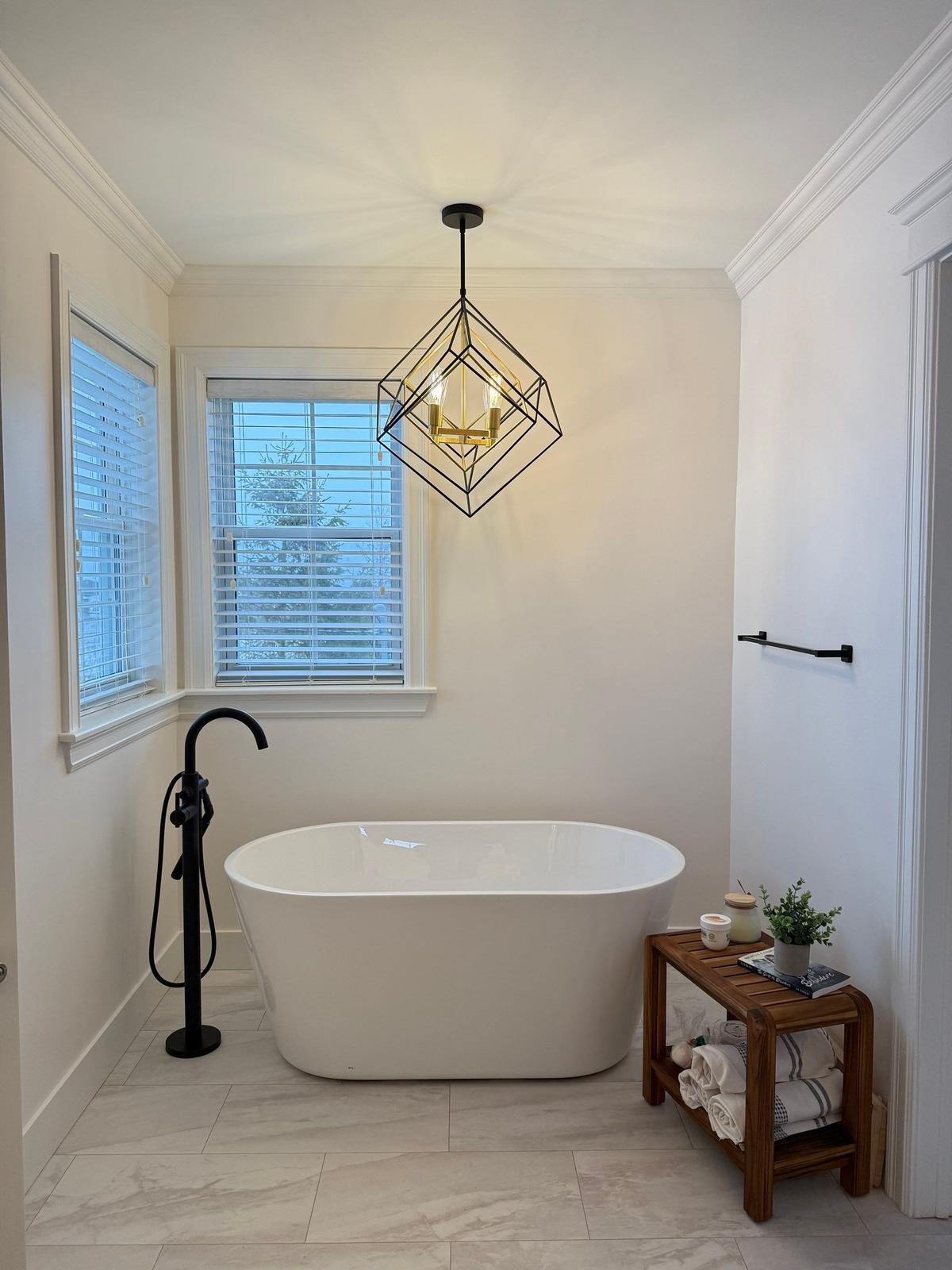 Motion Lane — freestanding tub beneath a geometric chandelier.